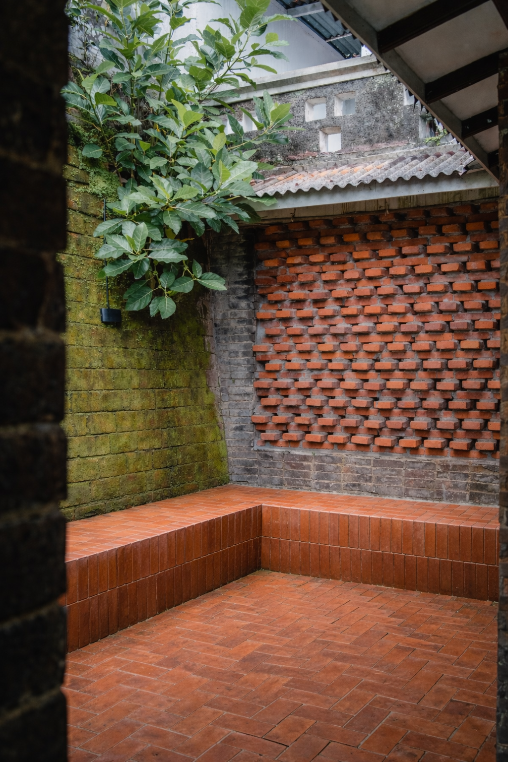 Terracotta brick courtyard wall with mossy patina